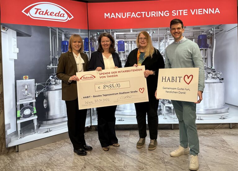 Gruppenbild bei Spendenübergabe vor Takeda-Schild posieren vier Vertreter*innen von HABIT und Takeda