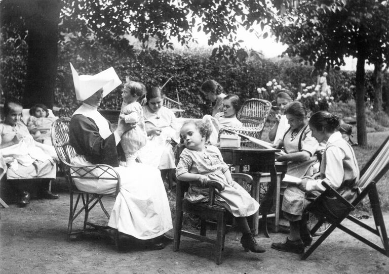 Ein Bild aus alten Zeiten: Schwestern mit ihren jungen Schützlingen im Garten.