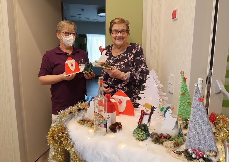Eine Bewohnerin und eine Mitarbeiterin sehen sich den mobilen Weihnachtswagen an.