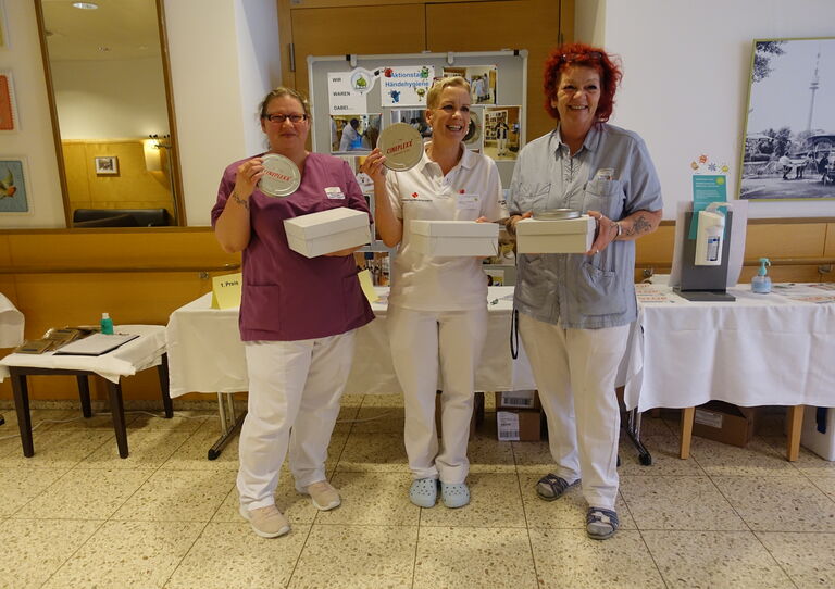 Kolleg*innen aus der Tokiostraße stehen zusammen und halten die Hände in die Kamera.