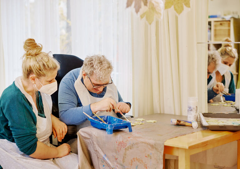 BTZ Maria-Rekker-Gasse: Mitarbeiterin und Kunde basteln gemeinsam.