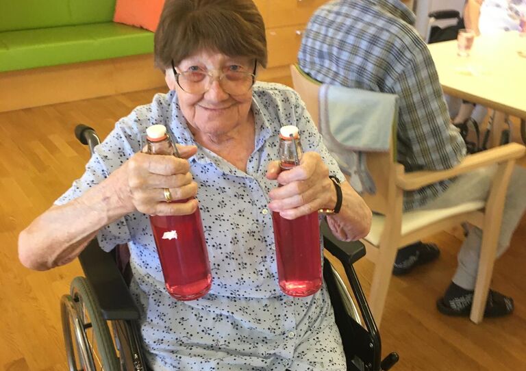 Eine Bewohnerin hält zwei Flaschen Lavendelsirup hoch.