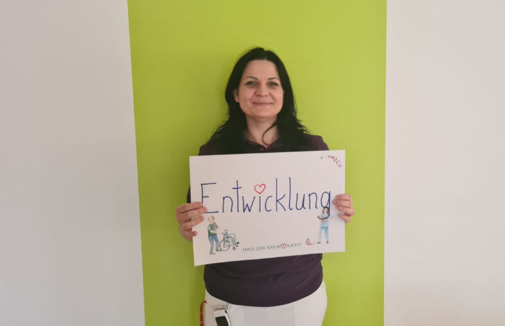 Mitarbeiterin hält Schild mit Entwicklung.