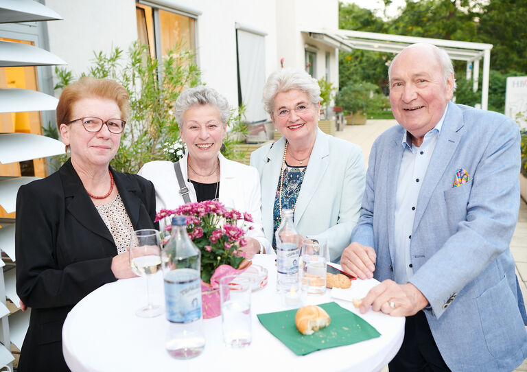 Vier Großspender*innen stehen an einem Tisch