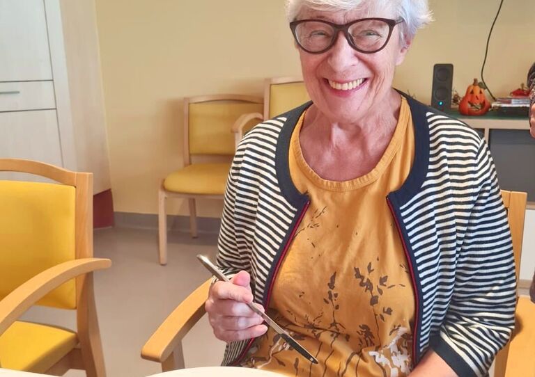 Eine glückliche Bewohnerin mit einem prall gefüllten Teller Essen.