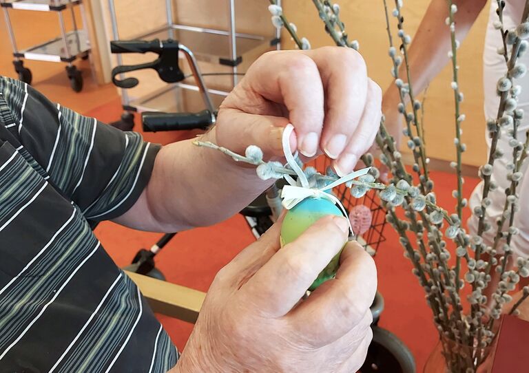 Ein Osterei wird auf den Strauch gehängt.