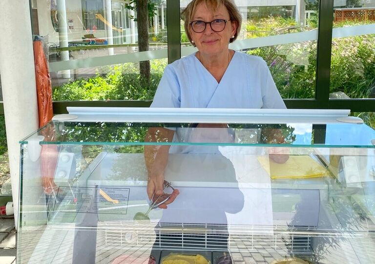 Eine Mitarbeiterin steht hinter einem Eiswagen, um Eis auszugeben.