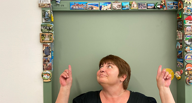 Gorica Popovic steht im Türstock in ihrem Büro und zeigt auf die vielen Magnete, die rund herum befestigt sind.